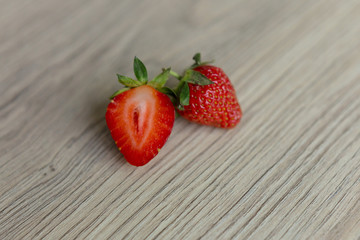strawberry on wooden background. red ripe strawberries. one whole and half strawberries. red berry