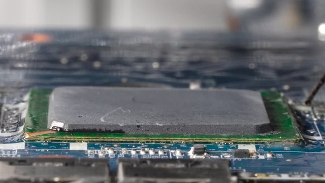 Boiling flux paste around the grid array microchip. Desoldering a microprocessor from the pcb located on the bga rework station. Closeup macro.