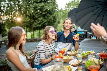 Young friends having fun together with snacks and drinks during the evening light outdoors in the...