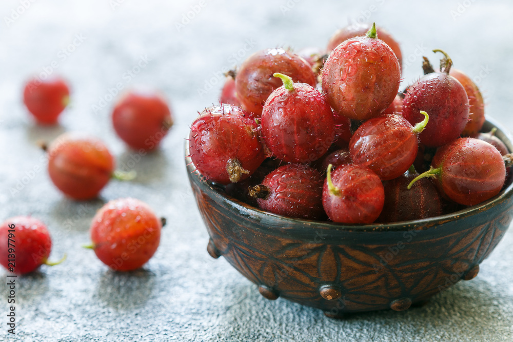 Wall mural fresh ripe organic gooseberry in a plate on the table. summer garden berry close-up.