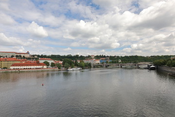 Fototapeta na wymiar Striking view from the Charles Bridge to the Vltava river, old architecture and modernity