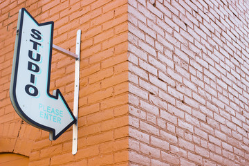 Obraz premium Old Vintage Arrow Studio Sign Pointing on an Urban Brick Wall