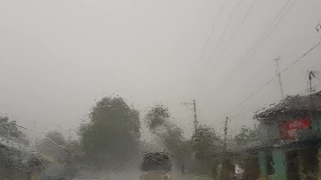 A windshield view inside the car while raining heavily. The windshield wipers are turned on.