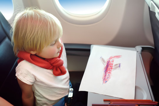 Joyful little boy sitting by aircraft window during the flight