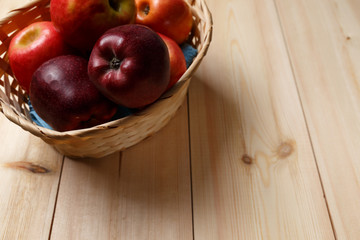 Ripe red apples in a basket on a bright wooden background. Top view