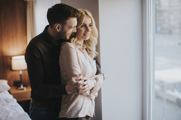 Young couple standing by the window in the room