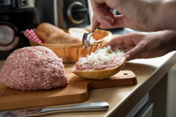Frau belegt Mett Brötchen mit Zwiebeln für deftige Deutsche Brotzeit