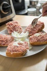 Frau belegt Mett Brötchen mit Zwiebeln für deftige Deutsche Brotzeit