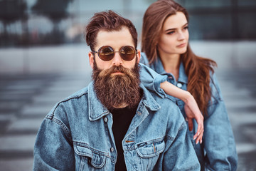Close-up portrait of a hipster couple of a brutal bearded male in sunglasses and his girlfriend...