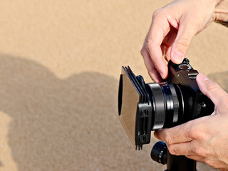 A photographer using a mirrorless camera and filters to do landscape photography. 