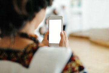 Woman's holding smart phone with blurred background.