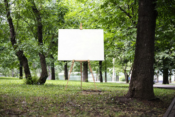 Easel with canvas and green park or forest on the background, 3d rendering.