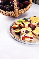 Rustic plum cake on wooden background with plums around.