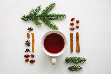 A cup of fragrant and tasty herbal or red tea on a white surface decorated in a Christmas style