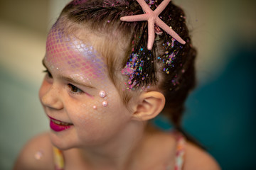 Portrait of a beautiful young mermaid girl at salon getting makeup on