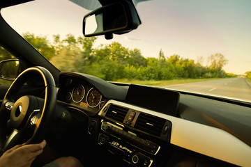 White car is driving on empty countryside asphalt road at sunset. Inside view from interior by...