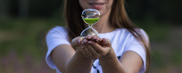 A girl holds an hourglass in her hands, close-up