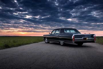 Zelfklevend Fotobehang Zwarte retro vintage muscle car staat geparkeerd op de asfaltweg op het platteland bij gouden zonsondergang © Ivan Kurmyshov