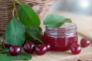 Cherry jam and basket of fresh cherries on a wooden table. Cherry in the nature