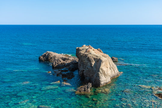 Crystal clear turquoise blue ocean waters. South east coastline with pebble stones and rocks, Grete Greece. Travel vacation concept.