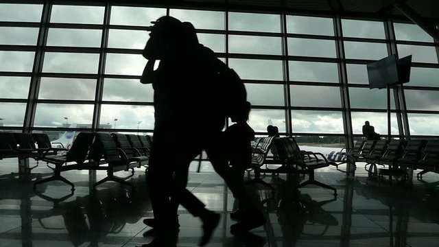 Unrecognizable passengers walking inside the air terminal, airport lounge, people silhouettes walking