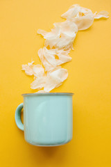 Creative idea. A mug from which white petals flew out like steam from a hot drink in the winter