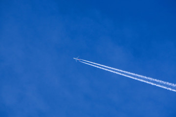 The plane with an inverse track is high in the blue sky.