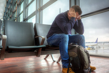 Depressed man waiting for the delayed plane departure