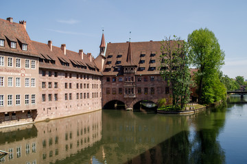 Fototapeta na wymiar Bridge over the Pegnitz river with a traditional half-timbered house and tower on the riverbank in the Old town of Nuremberg, Bavaria, Germany.
