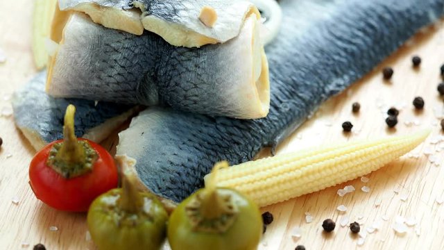 Saltwater marinated fish, cold appetizer. Herring fillet marinated on wooden cutting board