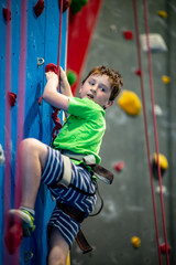 Young boy climbing up on practice wall in indoor rock gym