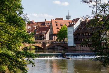 Fototapeta na wymiar Bridge over the Pegnitz river with a traditional half-timbered house and tower on the riverbank in the Old town of Nuremberg, Bavaria, Germany.