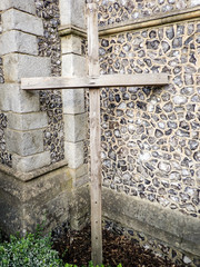Simple wooden cross by church wall