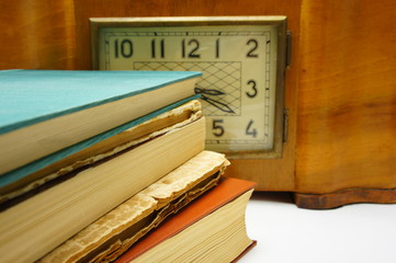 Old books on the background of old clock.
