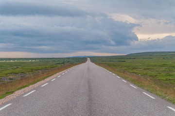 The road stretches into the distance on a background of green meadows