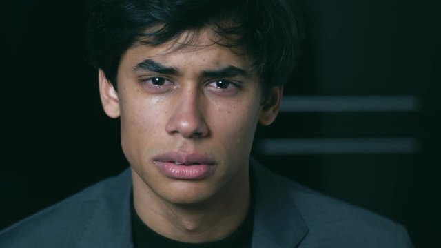sad and depressed young man cries looking at the camera