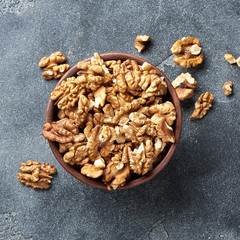 Walnut kernels in a clay bowl on a gray background. Close-up. Top view