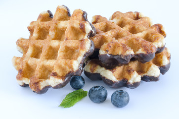 Waffles with chocolate and blueberries on white background.