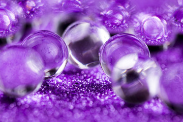 Crystal Gel water balls on purple glitter texture rotation. Close up macro footage.