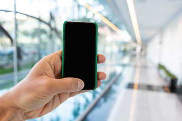 Close up of mobile phone with corporate environment blurred in the background.