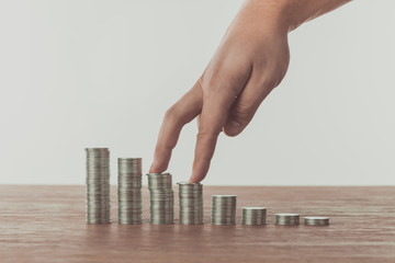 cropped image of man walking with fingers on stacks of coins on table, saving concept