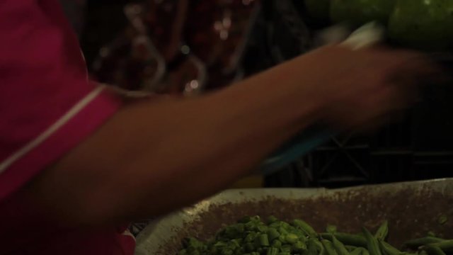 Hands of a woman selling the public market cutting green beans