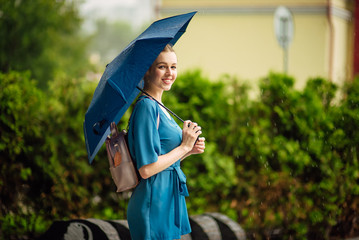 Young girl with blue umbrella . Summer rain
