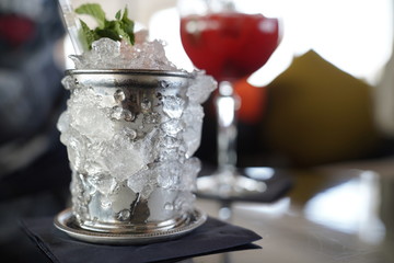 Beautiful cocktail in a metal glass covered by ice with mint on top