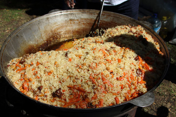Traditional Uzbek plov (lamb and rice pilaf) outdoor cooking in kazan