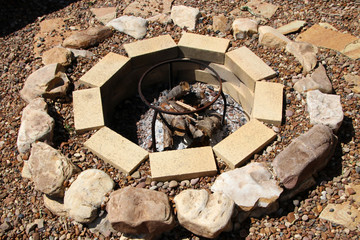 Fire pit with fuelwood surrounded by pebble in the summer garden