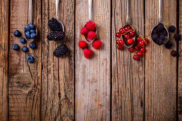 Berries on a vintage spoon on the Old Wooden Background.Blueberries, Raspberry, Strawberry Summer Vitamins. Top View.Copy space for Text. Healthy Food.
