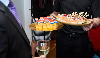 Waiter doing catering service, holding tray with appetizers canape snack