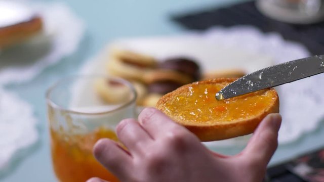 Traditional Italian Breakfast. spreading jam on rusk with knife