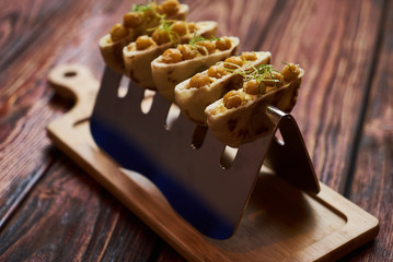 Labne and karri snack food with fried yellow peas, curry, lemon peel, in bread cake pita. Delicious vegetarian food on silver stand at luxury restaurant table